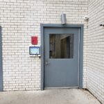 mvi keycom mounted on white brick wall by building entrance